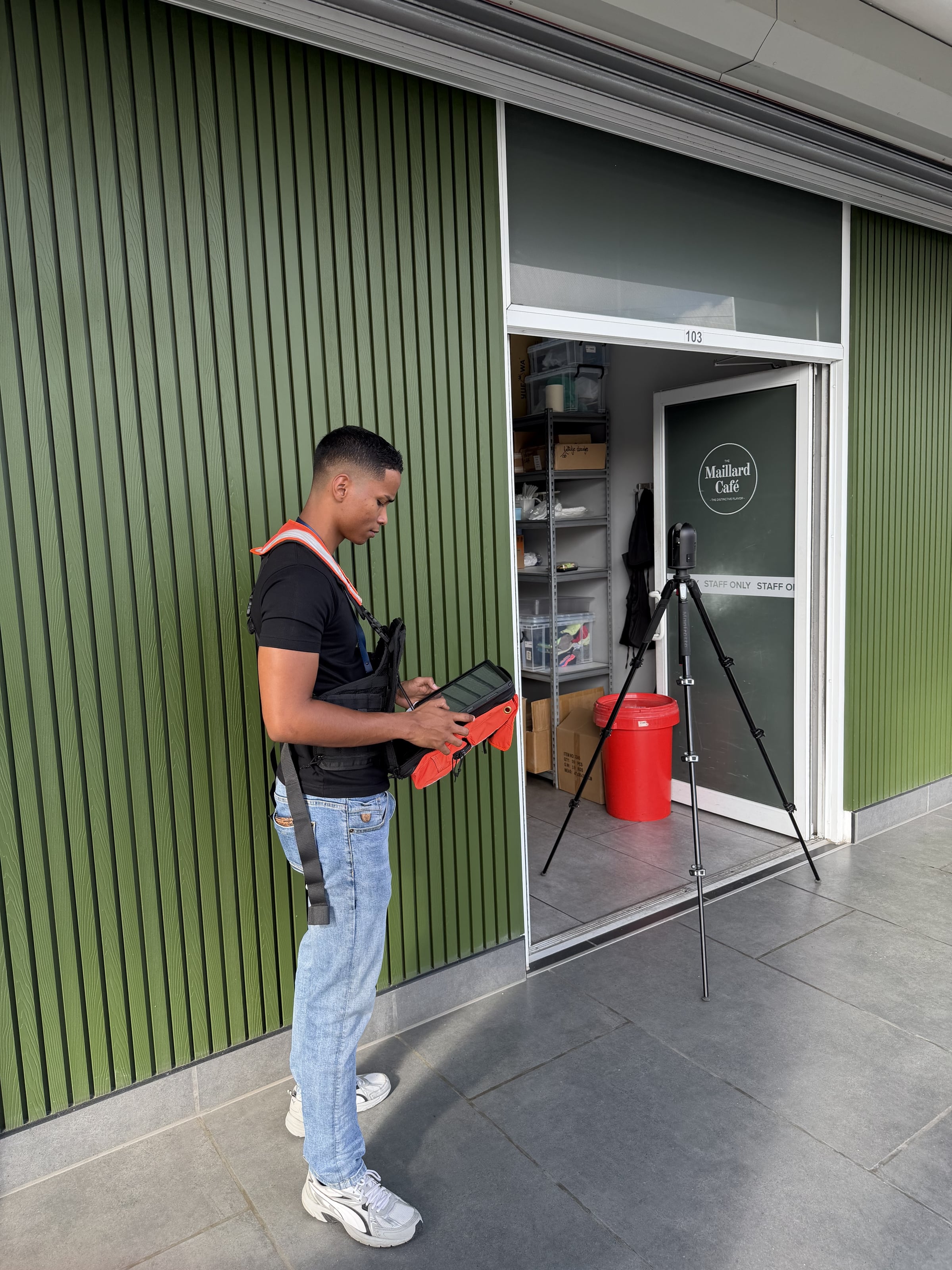 Collega meet de gevel van Maillard Cafe in met een scanner op statief